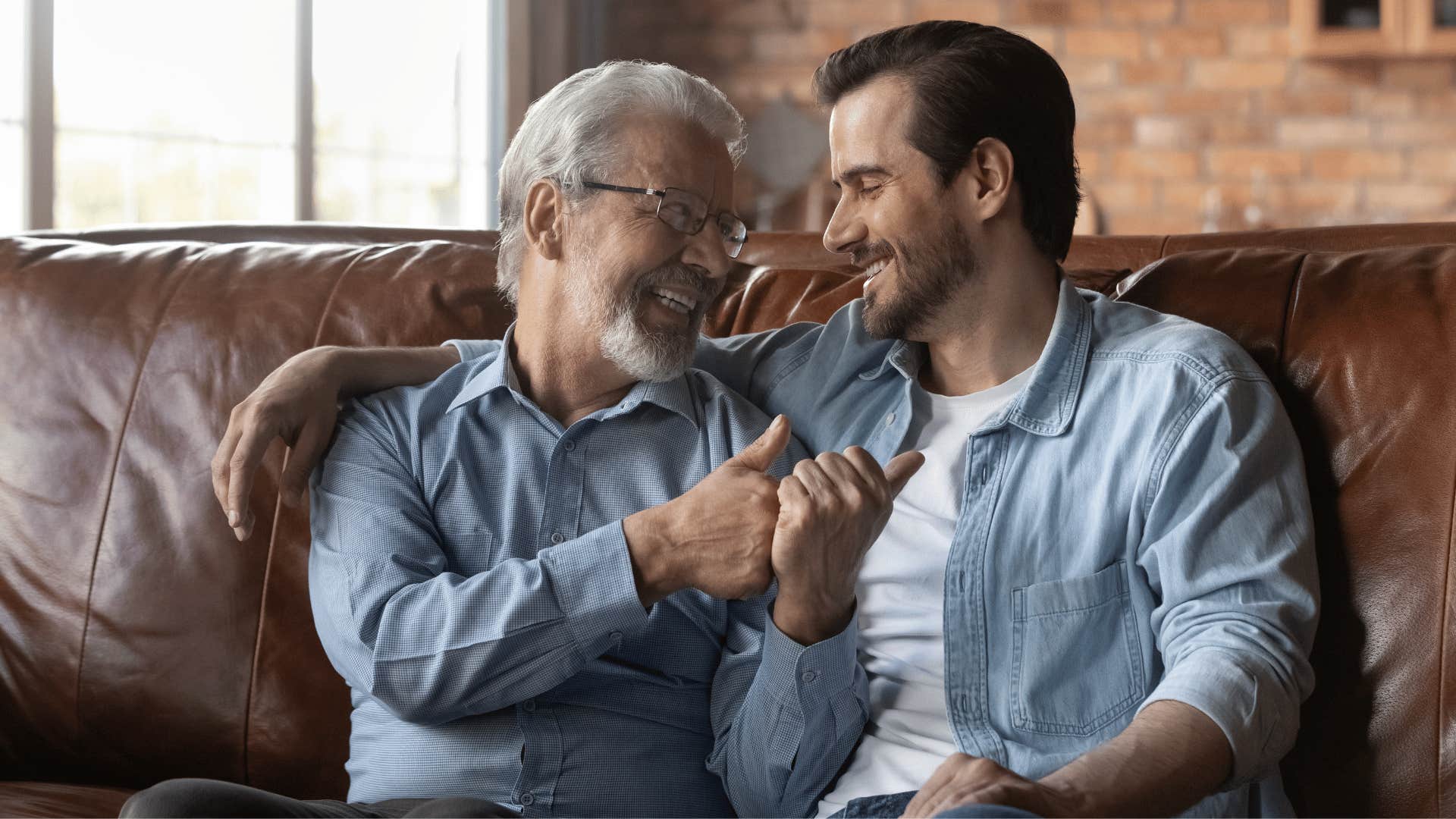 Grandfather and grown grandson talking on a couch 