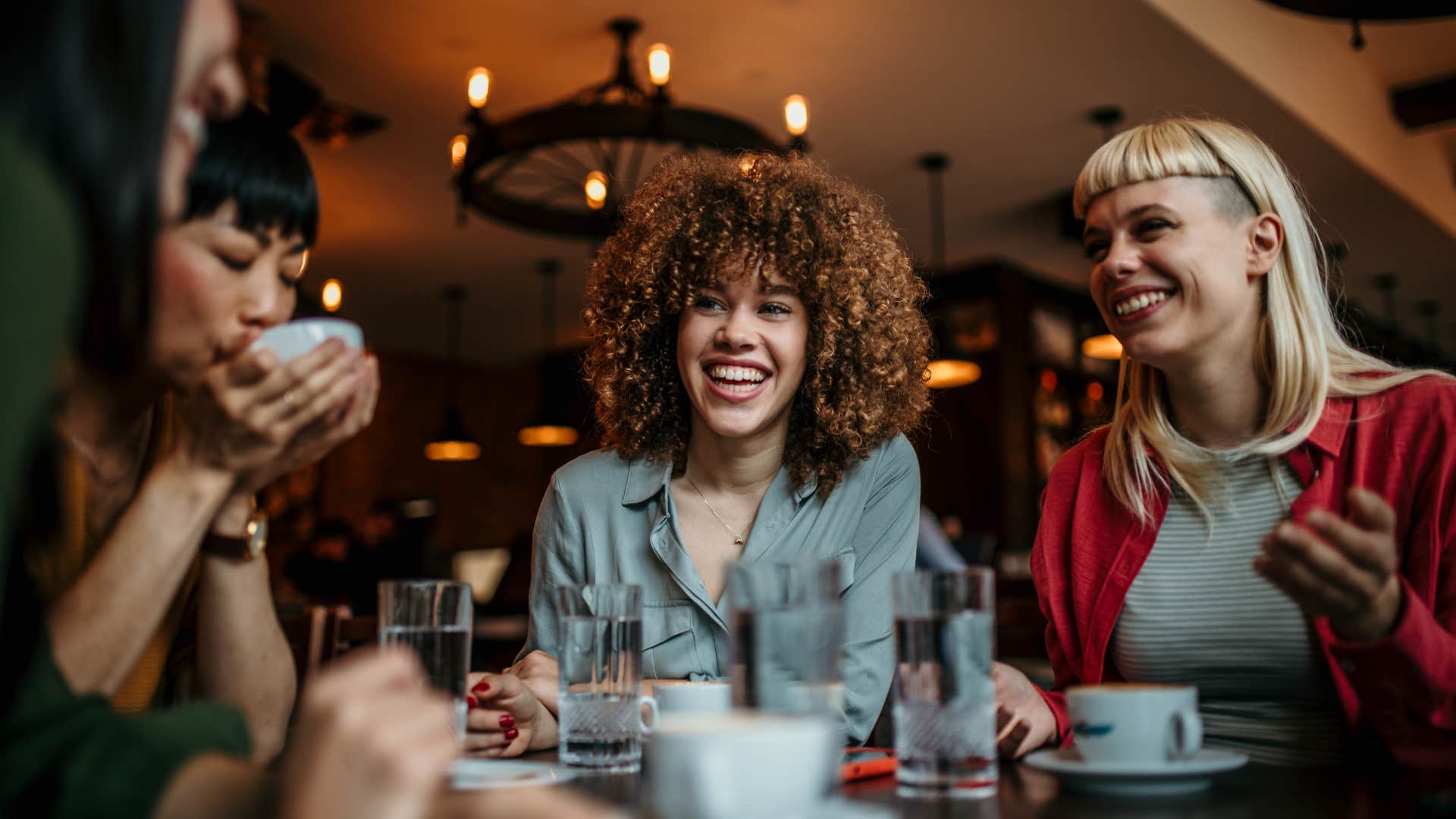 Woman who grew up with lots of money having dinner with happy friends 