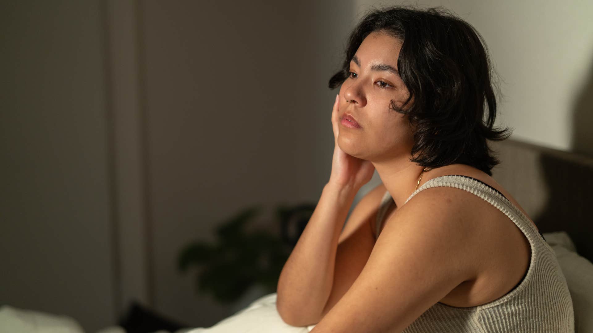 woman overthinking sitting in bed looking sad
