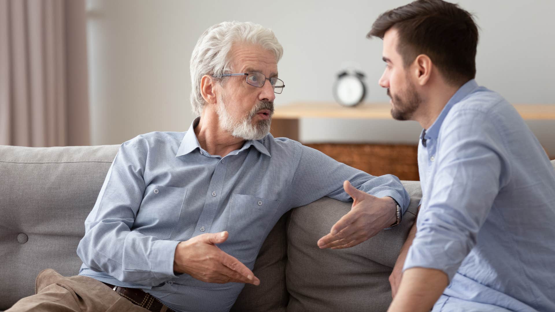 Toxic dad telling his son something very forcefully on a couch at home