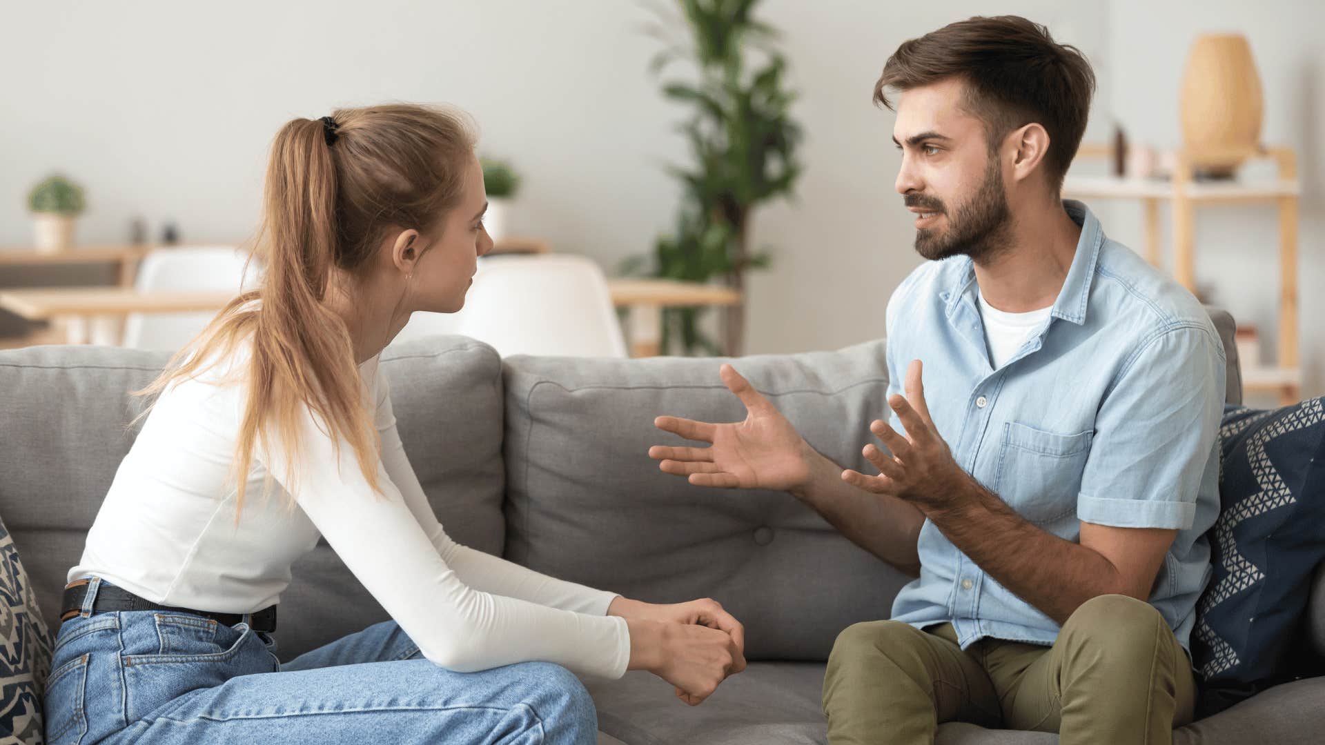 Controlling man arguing with a woman who loves him on their couch