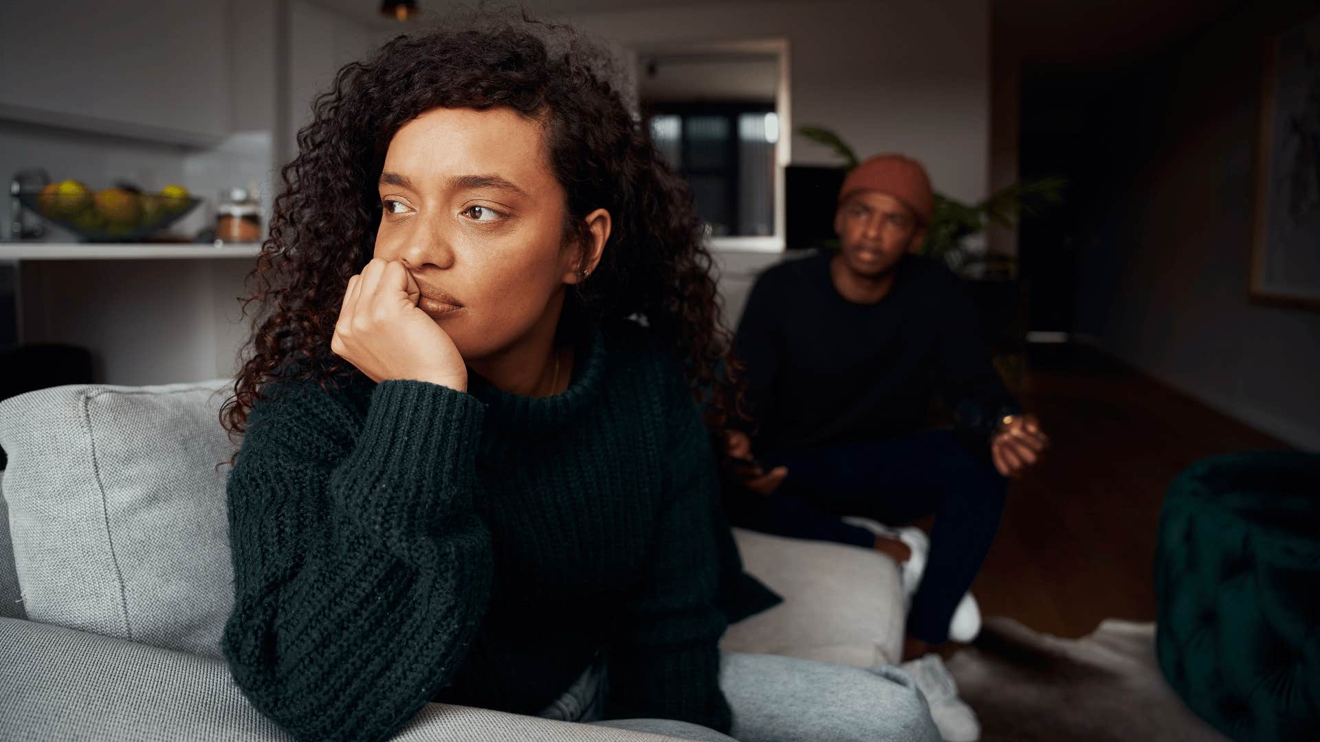 Woman tries to ignore a controlling man who is looking at her at home