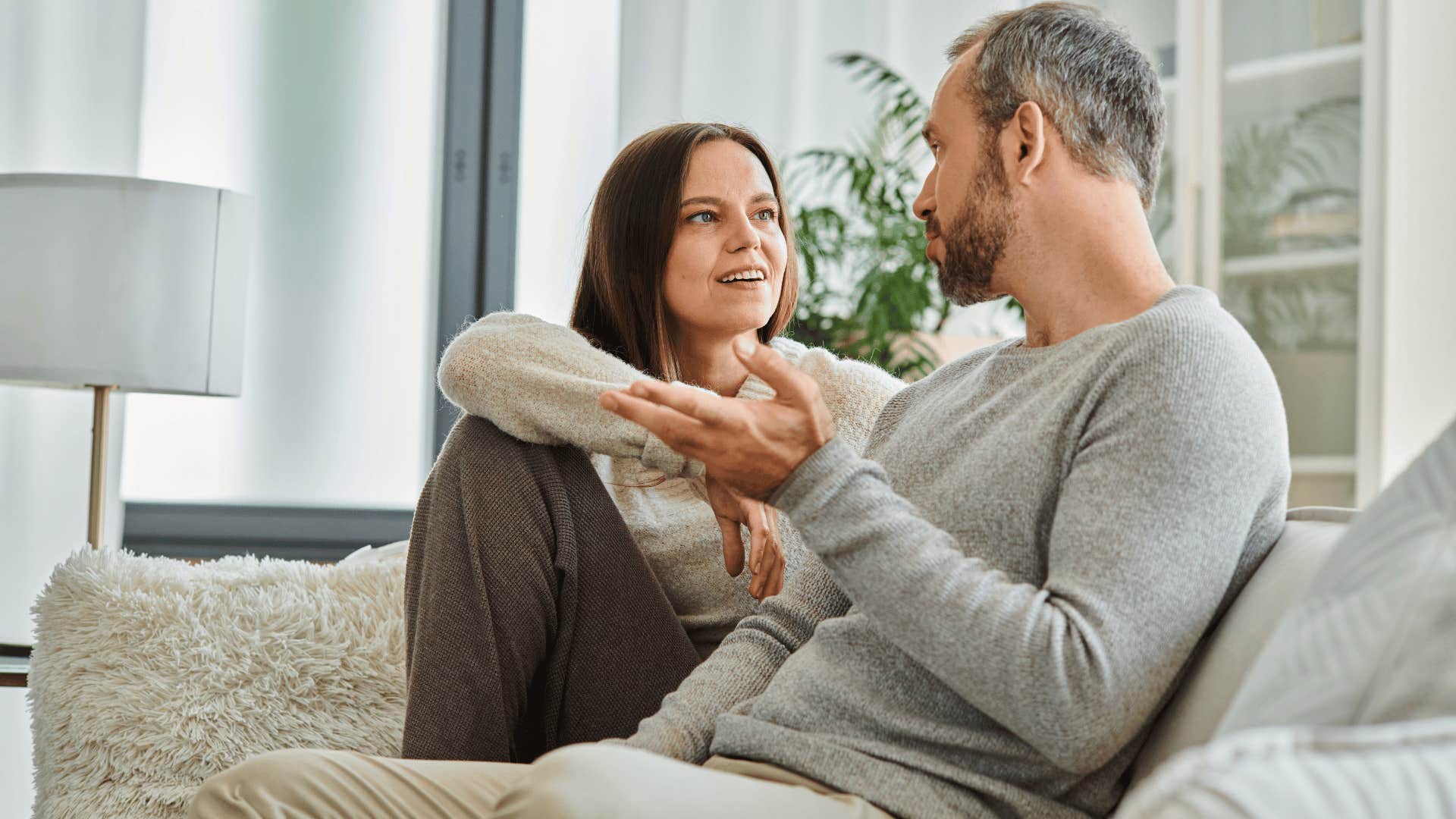 Woman smiling while a man talks to her on a couch 