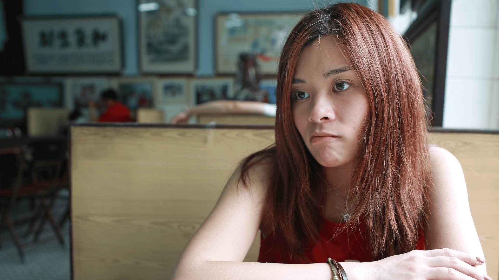 Grown adult daughter looking stressed in a diner alone