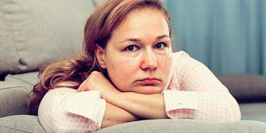 Adult child of toxic parents looking sad on a couch 