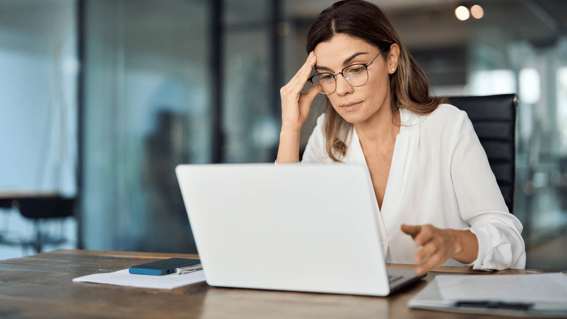 Woman looking overwhelmed and exhausted in a conference room at work