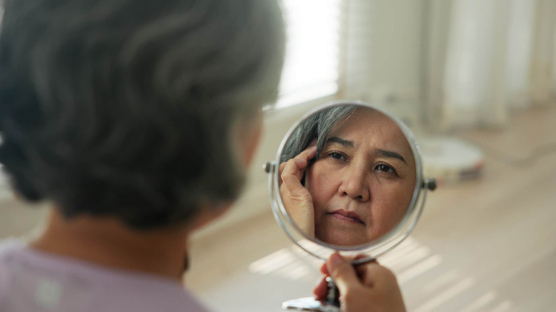 Contemplative person looks in mirror showing post-divorce awareness