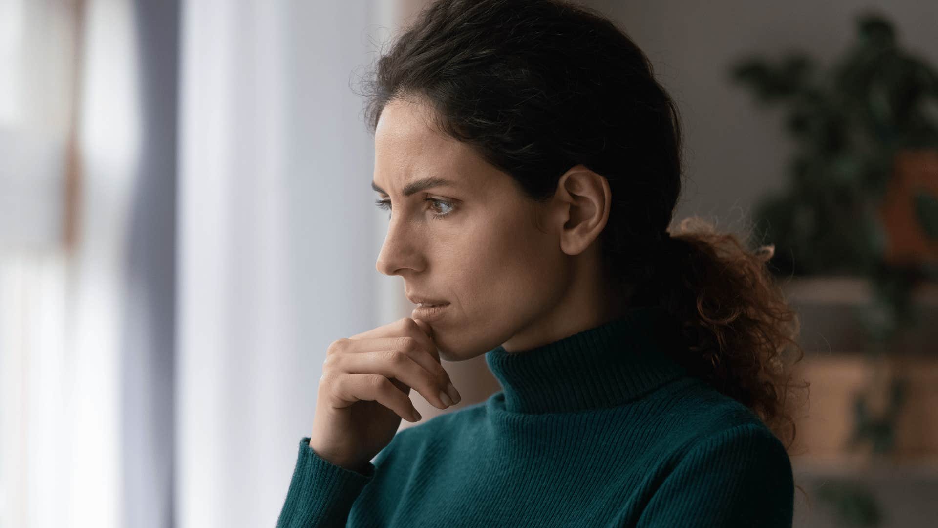 Mother of a Gen Z young adult looks stressed out a window 
