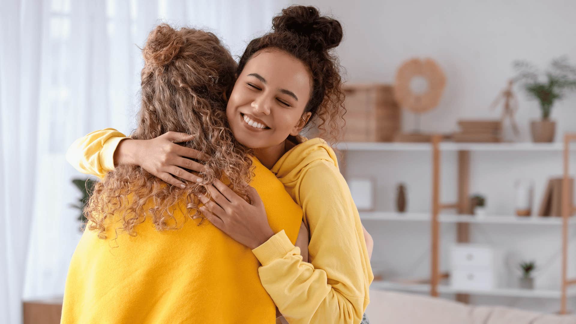 Young woman whose parents did exceptional job hugs her mother while smiling