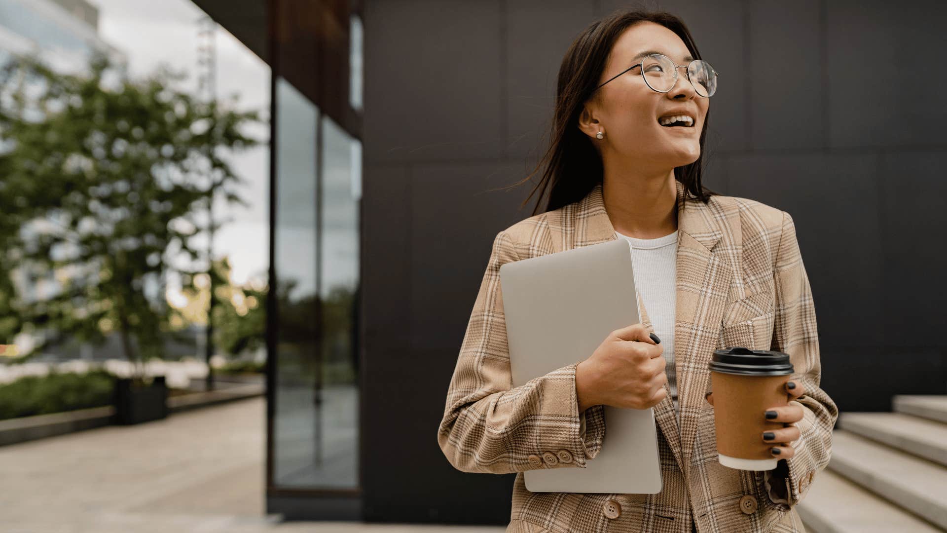 Business woman whose parents did an exceptional job smiles confidently with laptop